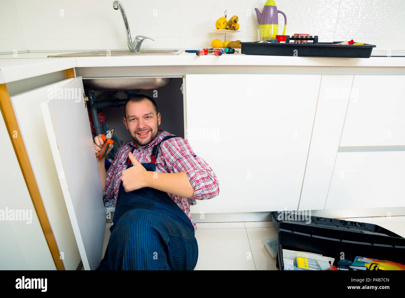 Worker repairs the leakage problem in the kitchen sink Stock Photo
