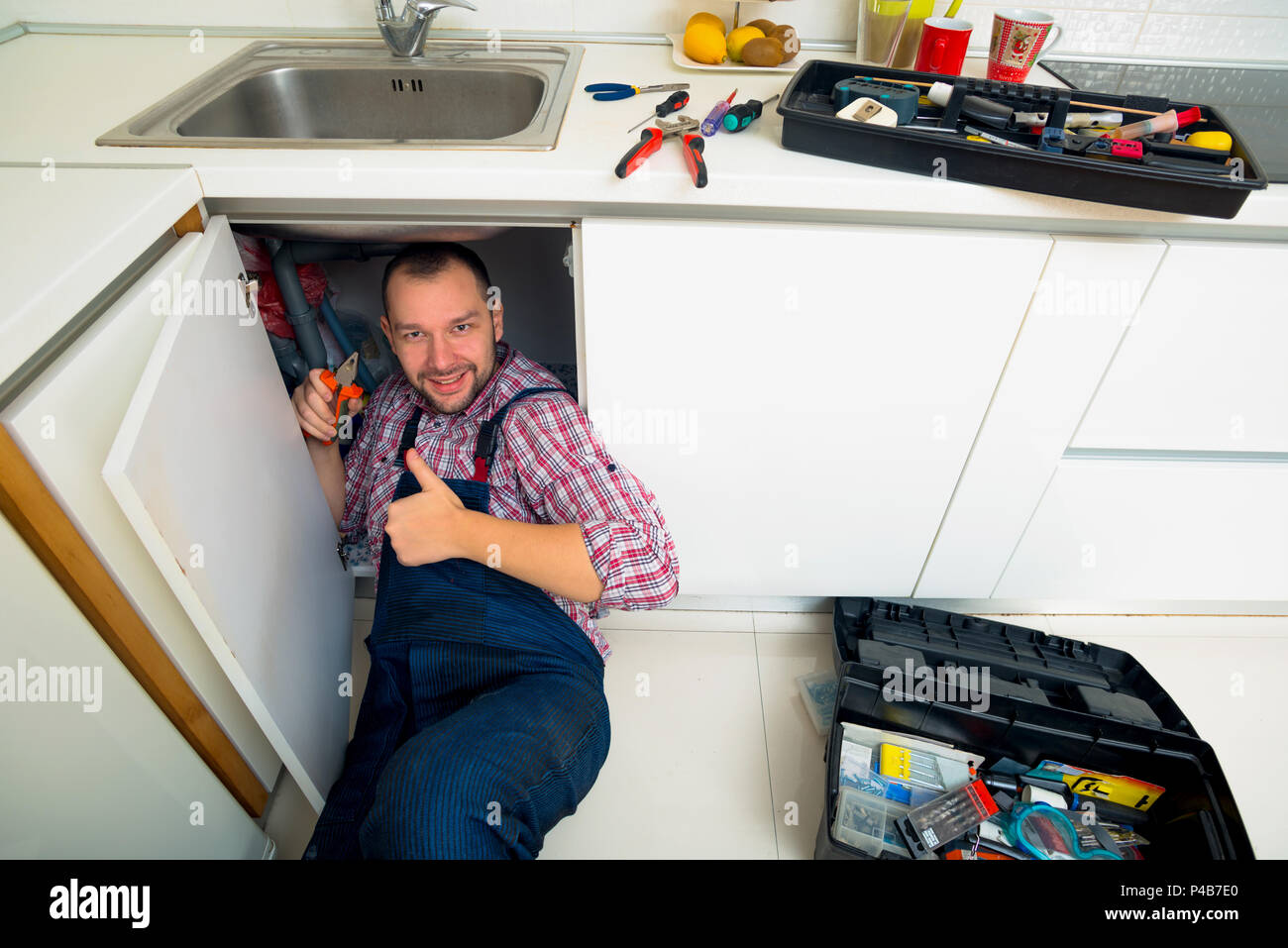 Worker repairs the leakage problem in the kitchen sink Stock Photo