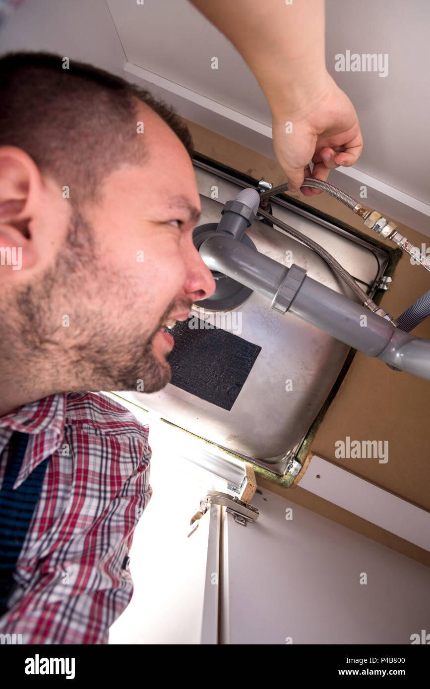 Worker checks for problem inside the kitchen sink, view from inside
