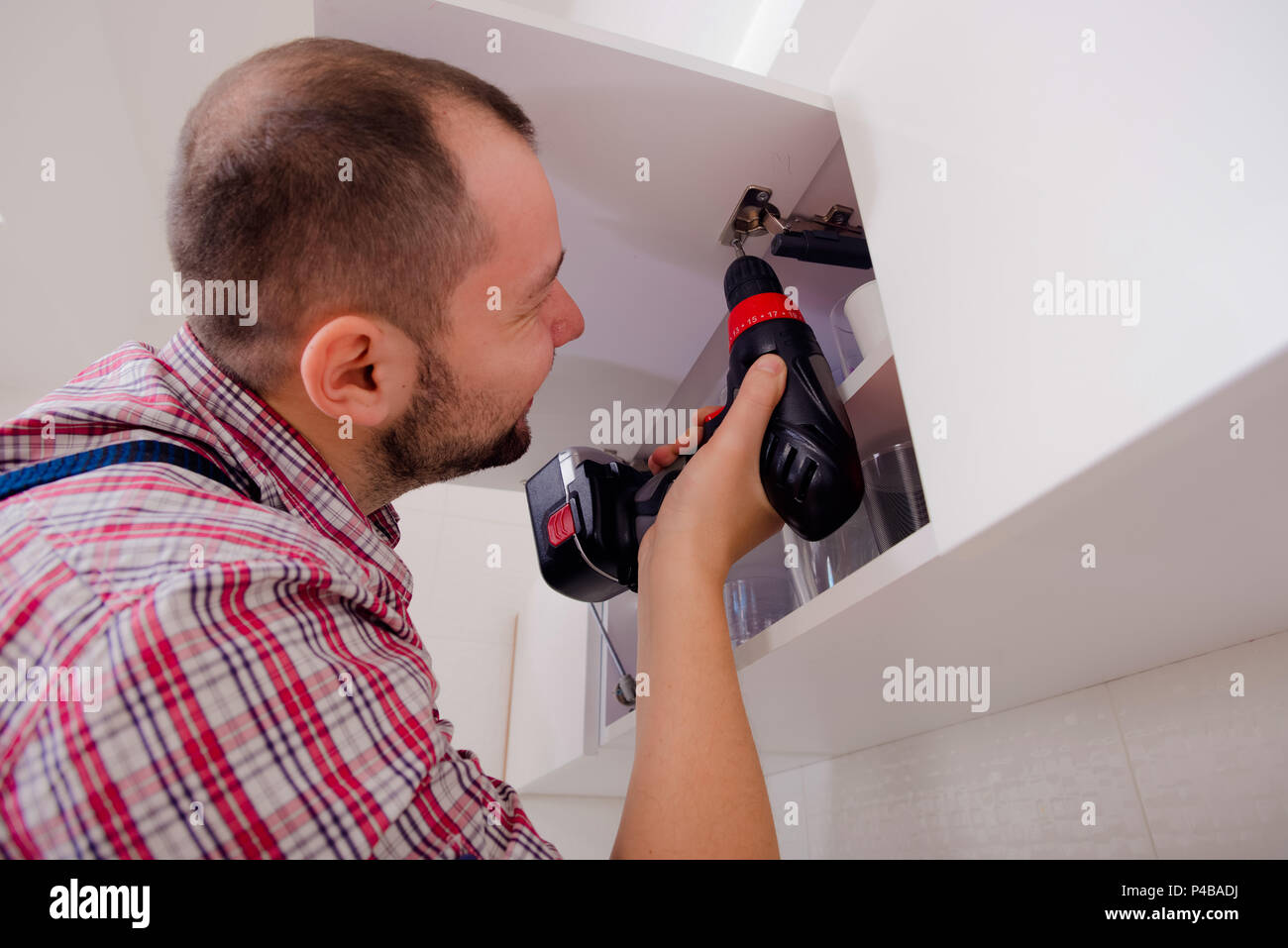 Handyman Fixing The Kitchen Cabinet Doors With Battery Drill Stock