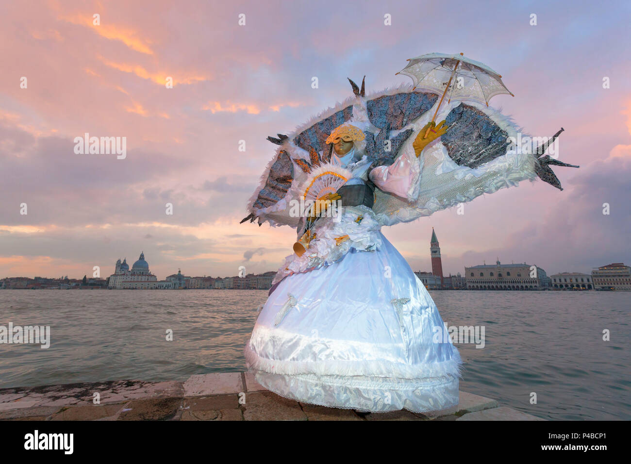 Typical mask of Carnival of Venice at San Giorgio island with Church of Santa Maria della Salute and San Marco Bell Tower on background, Venice, Veneto, Italy Stock Photo