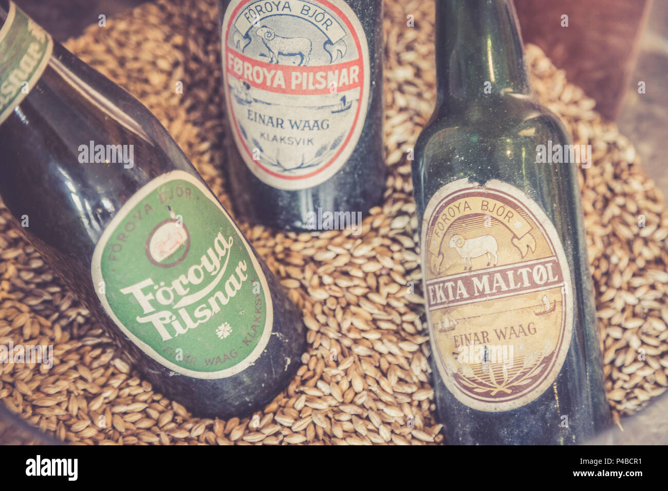 Close up of beer bottles on cereal grain background in the Foroya Bjor family brewery, Klaksvik, Bordoy Island, Faroe Islands Stock Photo