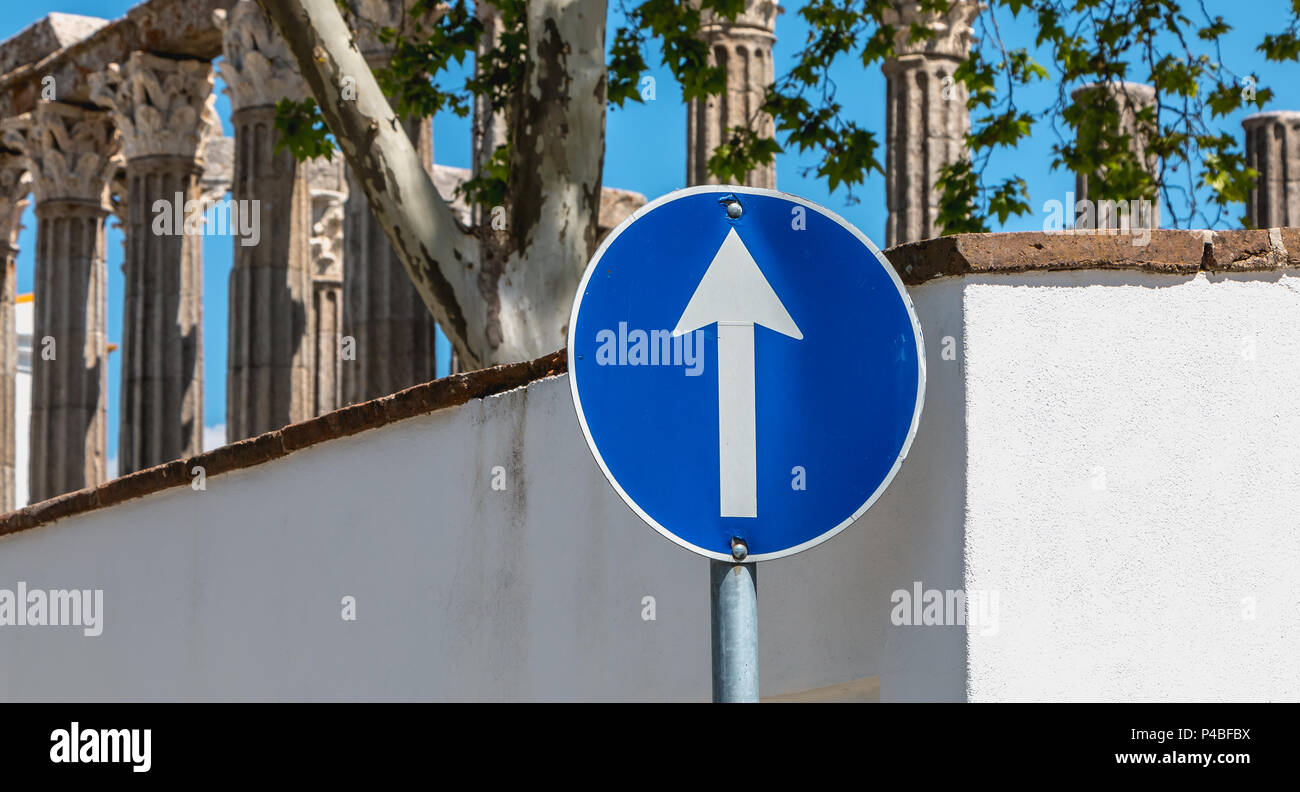 Blue round road sign ahead only in front of the ruins of a Roman temple of Evora Stock Photo