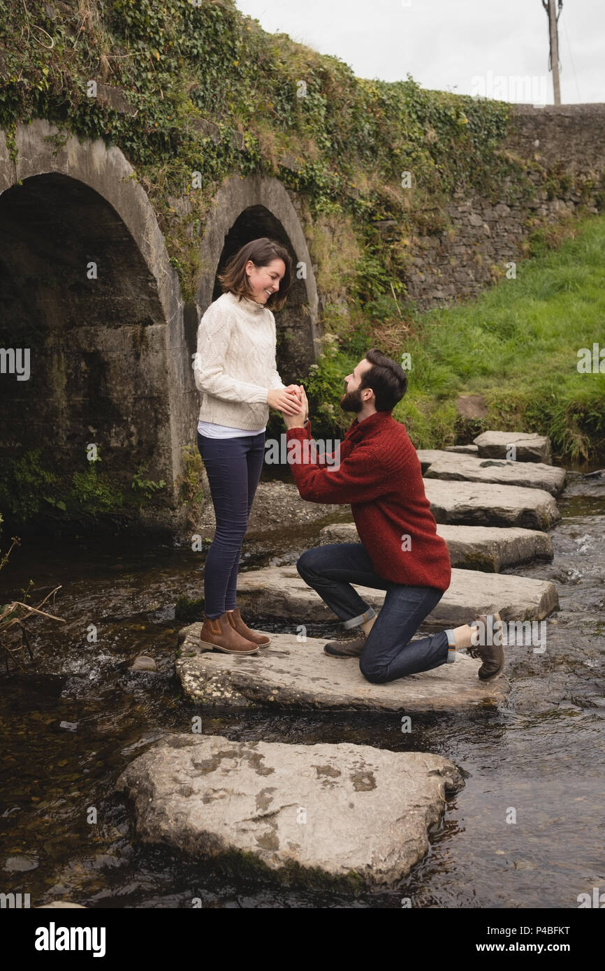 Man proposing woman on rock Stock Photo