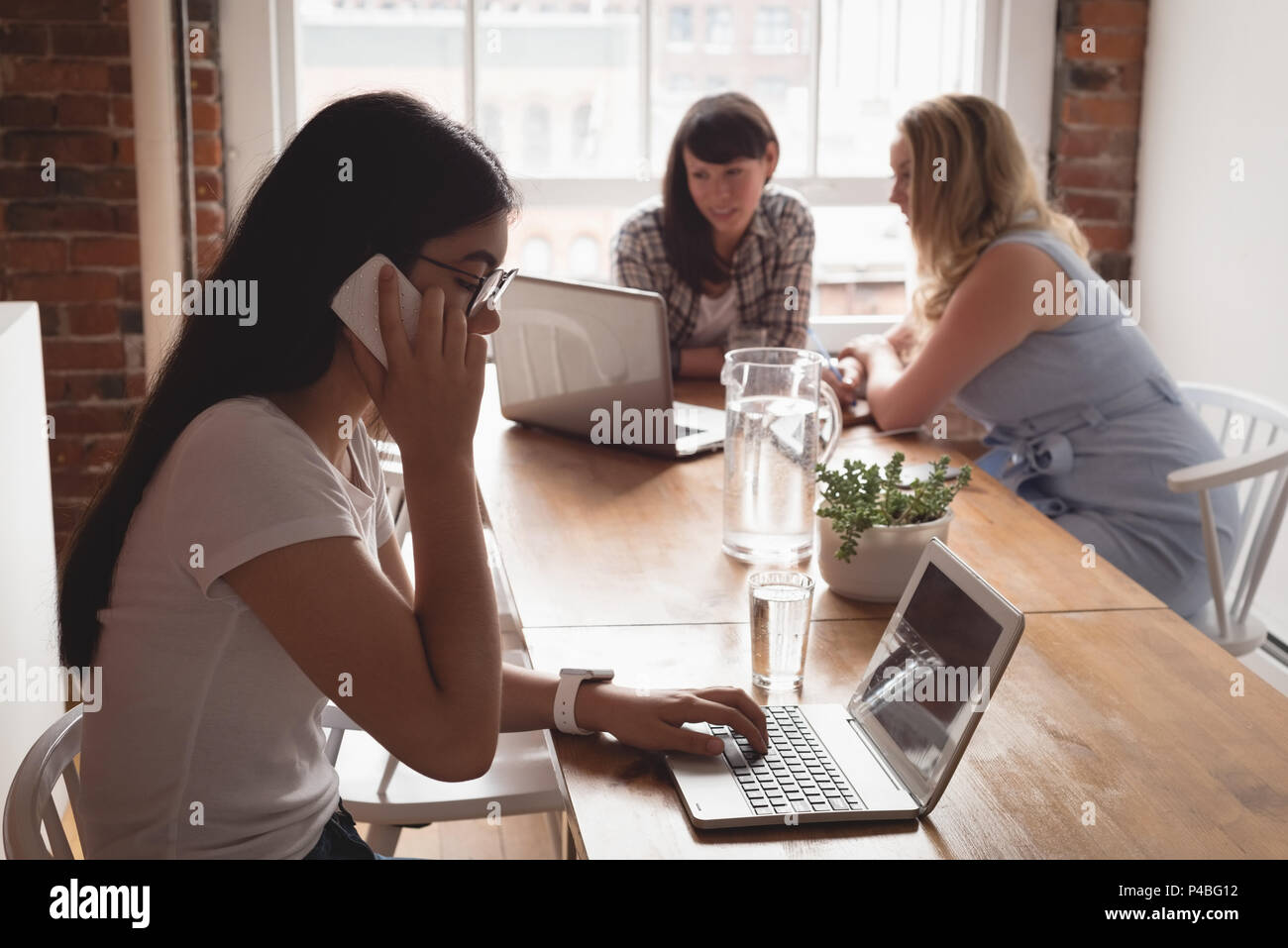 Executive talking on mobile phone while using laptop Stock Photo