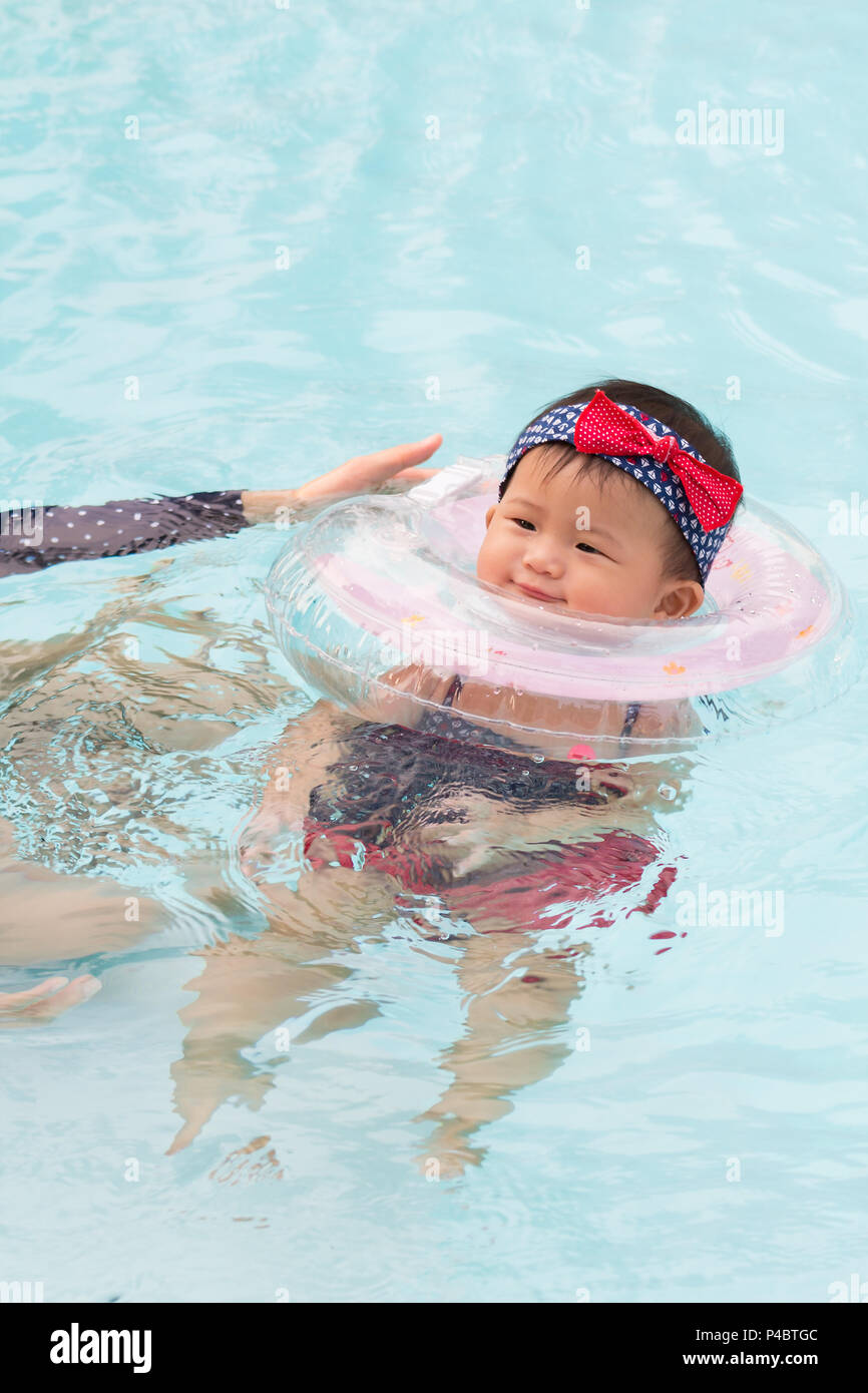 Asian young mother and cute eight month baby enjoying swimming pool