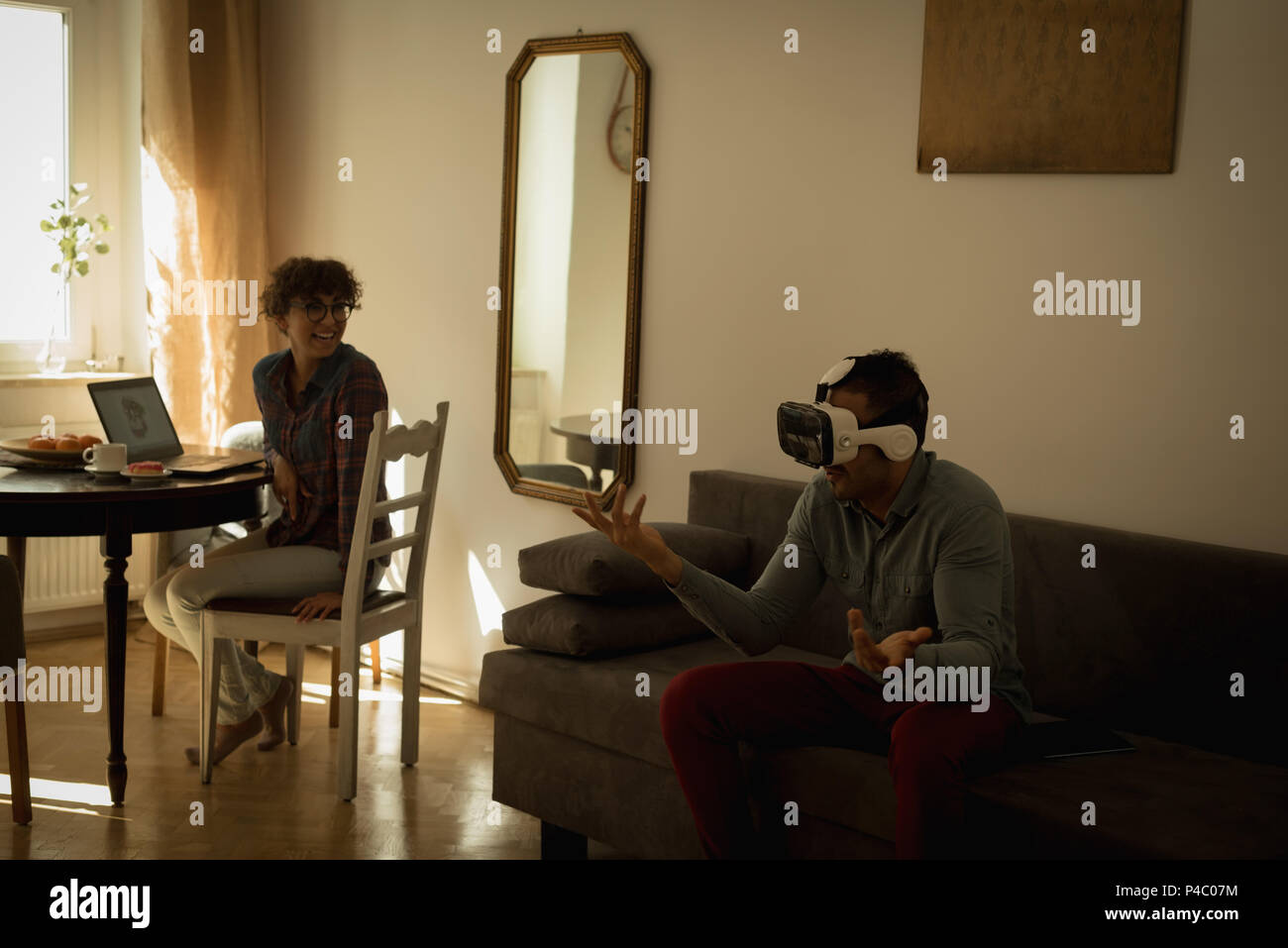 Woman looking at man while using virtual reality headset Stock Photo