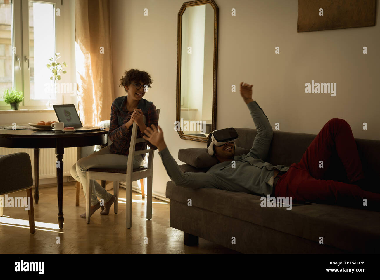 Woman looking at man while using virtual reality headset Stock Photo