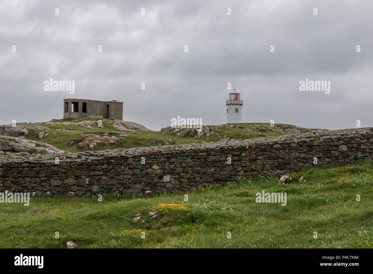 Fanad Head, a rocky headland in County Donegal Ireland, with a derelict coastal lookout building and Fanad lighthouse behind the stone perimeter wall. Stock Photo