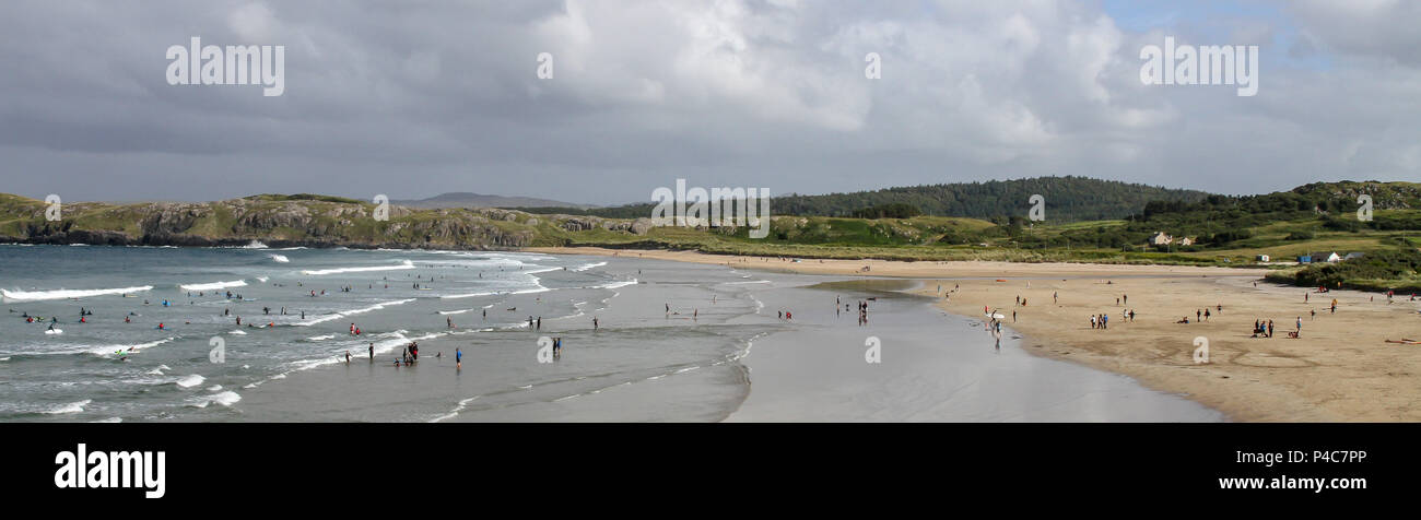 Surf schools and people surfing in County Donegal, Ireland, with people watching from beach. Stock Photo