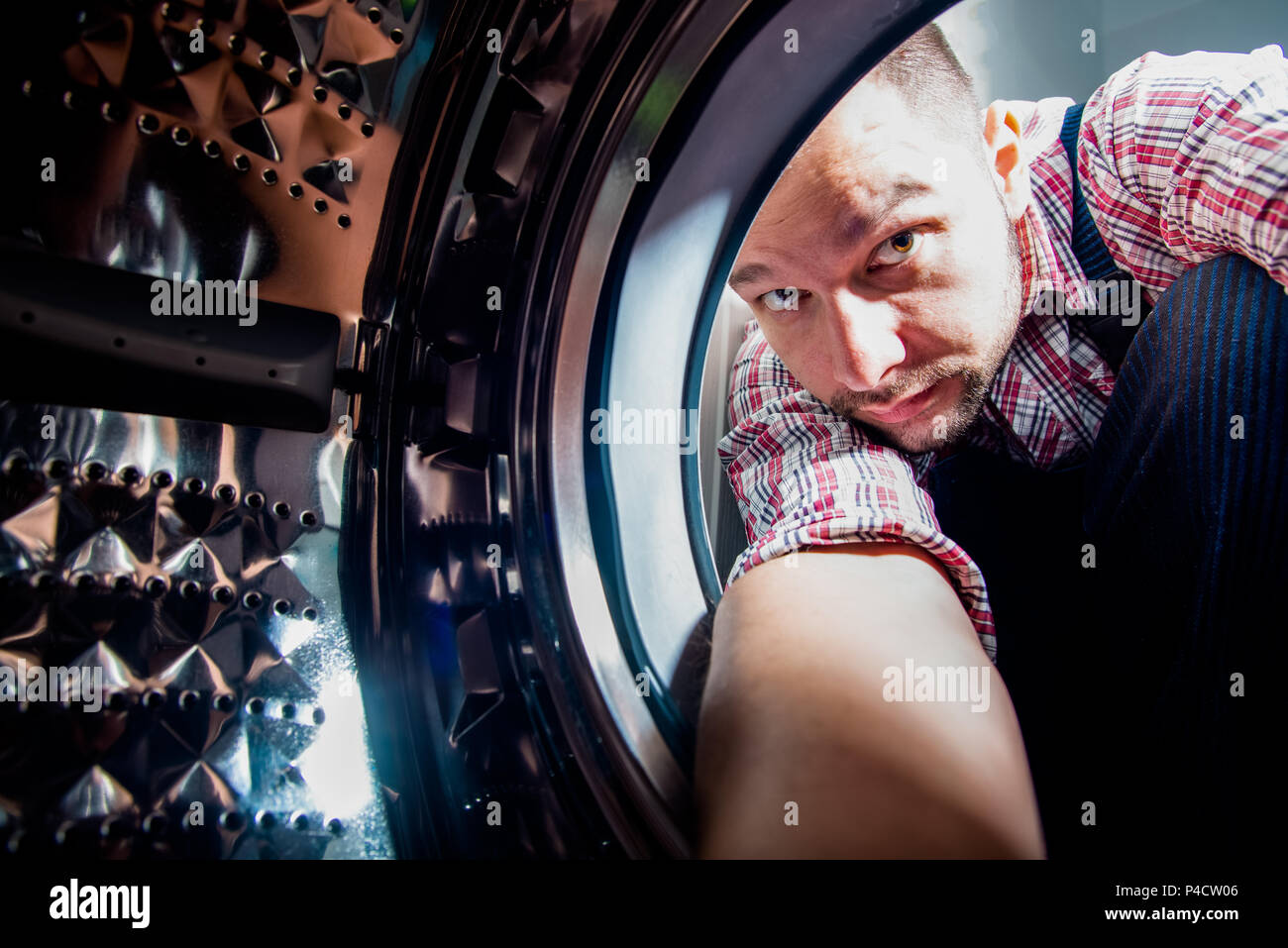 Repair man fixing the washing machine in the bathroom, view from inside