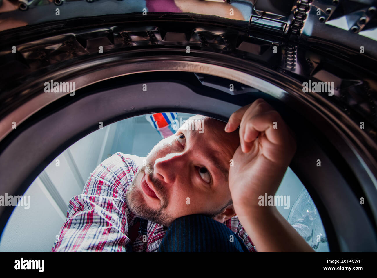 Repair man fixing the washing machine in the bathroom, view from inside