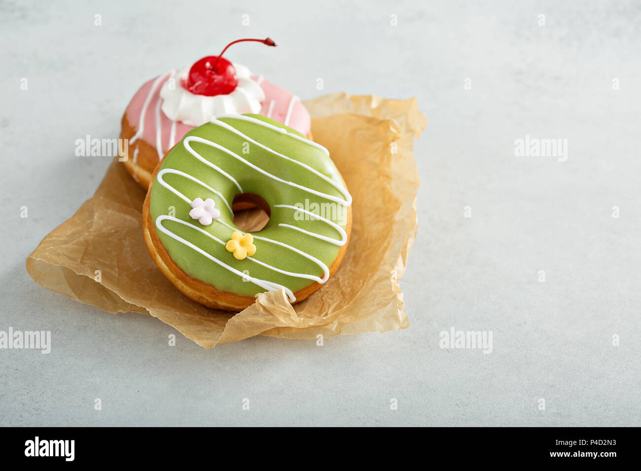 Assorted glazed fried donuts on parchment Stock Photo