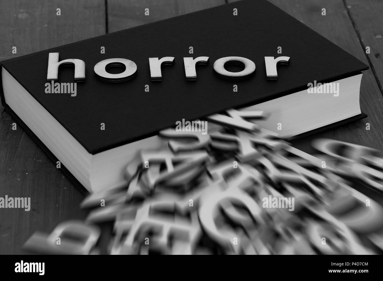 Book novel with the word horror and blurred letters coming out of the pages on a wood background Stock Photo