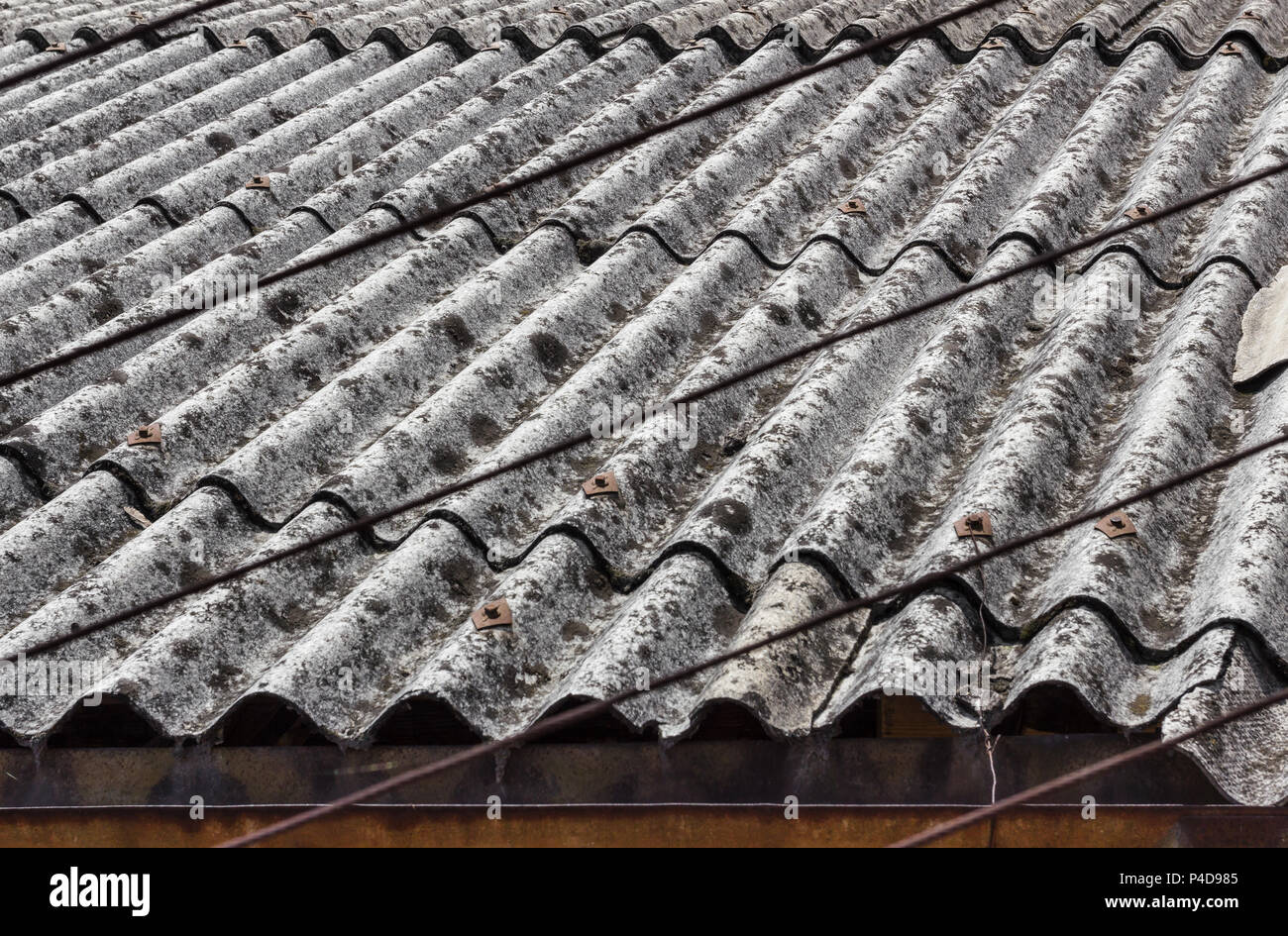 Old and dangerous asbestos roof, one of the most dangerous materials in the construction industry. Stock Photo