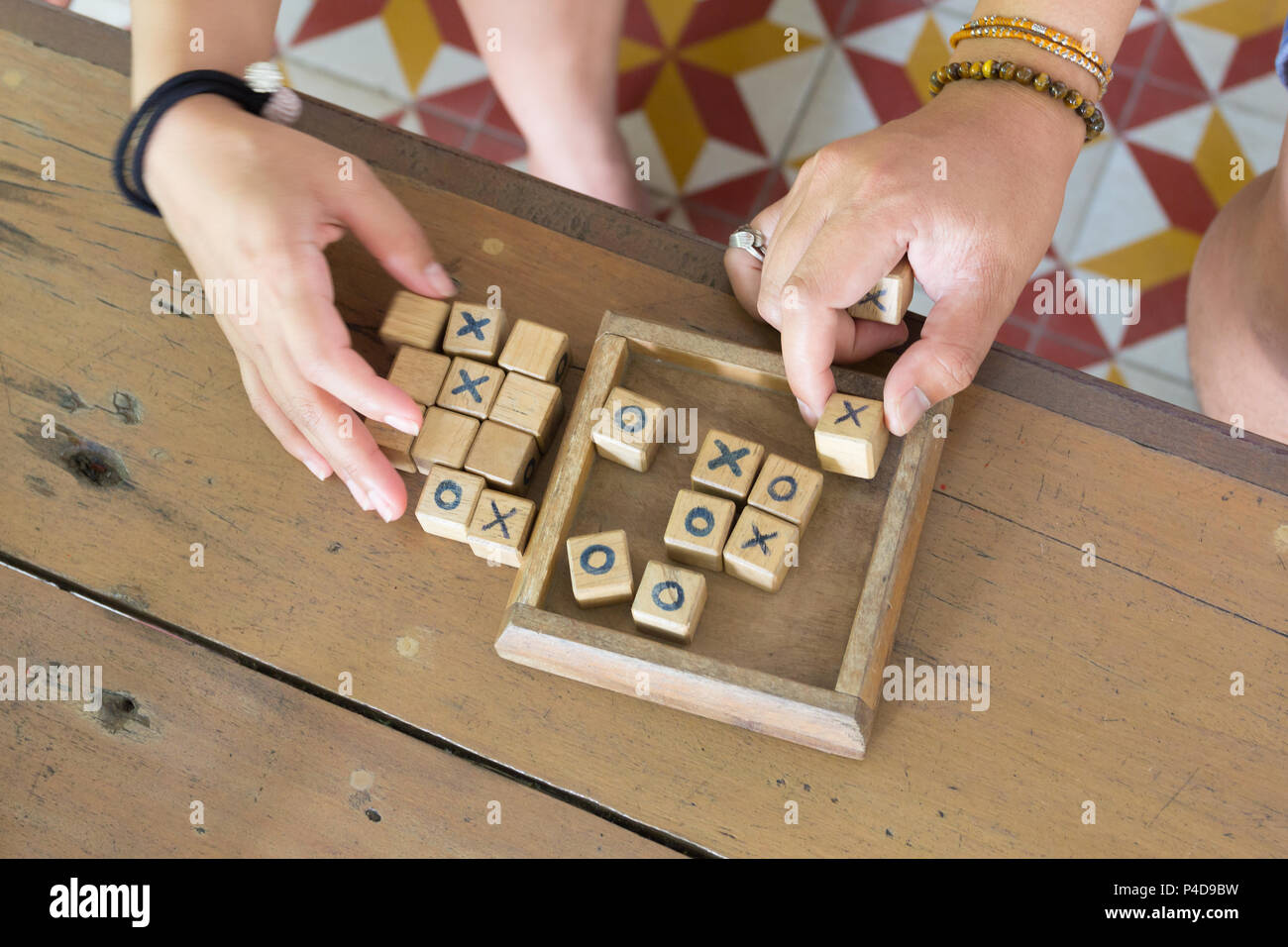 Wood toy is xo game, with hands players on wooden table background