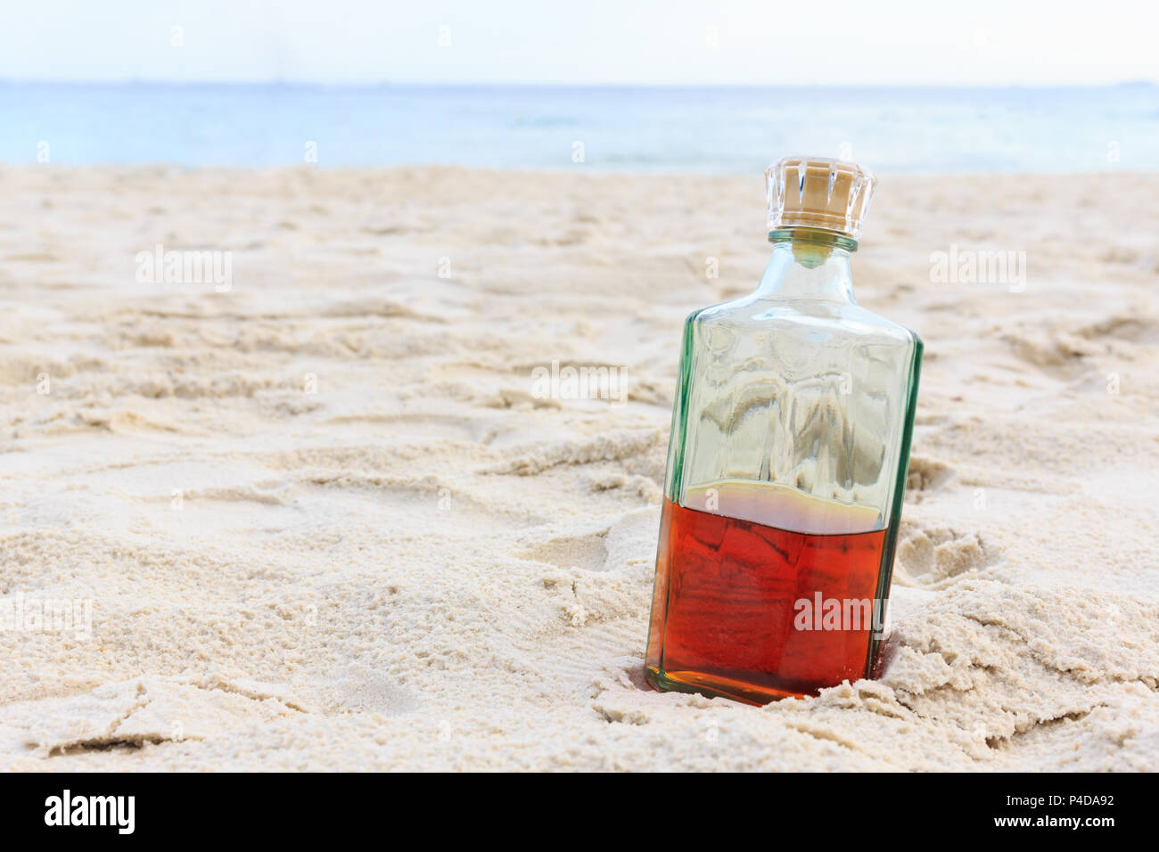Beverage alcohol is brandy bottle on sand beach background Stock Photo