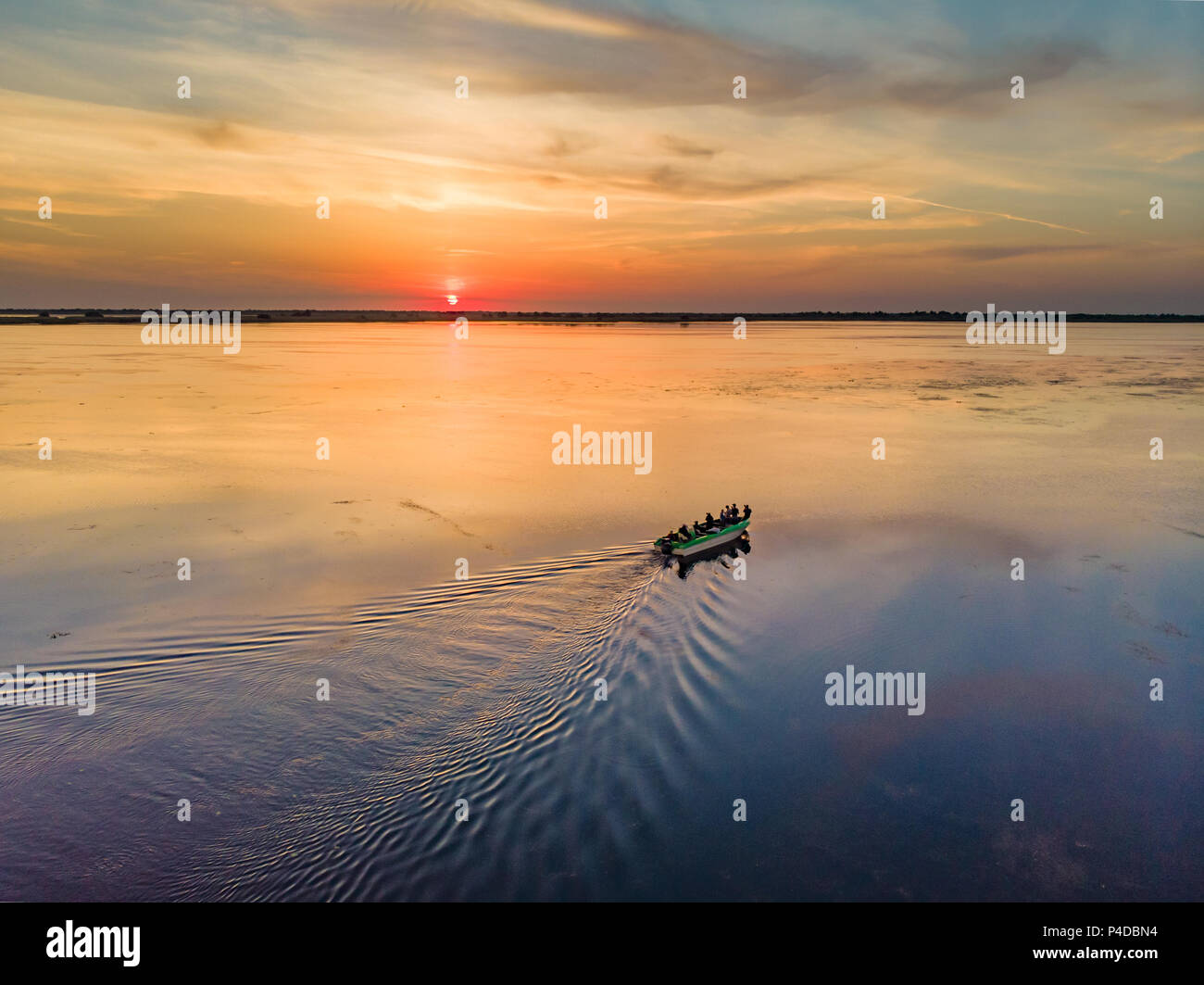 Tourists visiting Danube Delta at sunset in a motor boat. Sunset in Danube Delta (Delta Dunarii), Europe, Romania Stock Photo