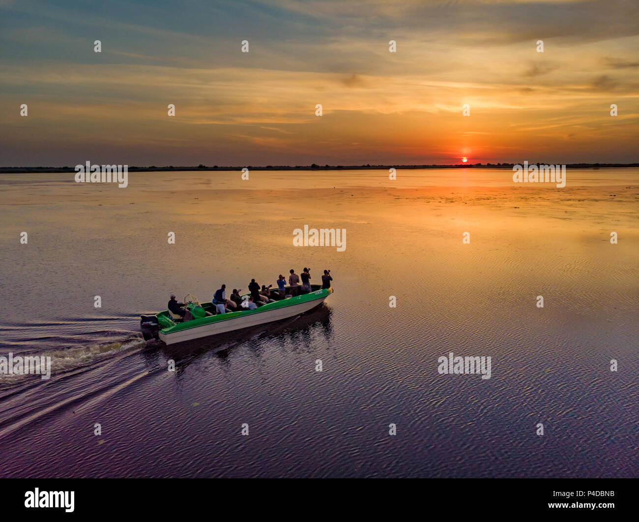 Tourists visiting Danube Delta at sunset in a motor boat. Stock Photo