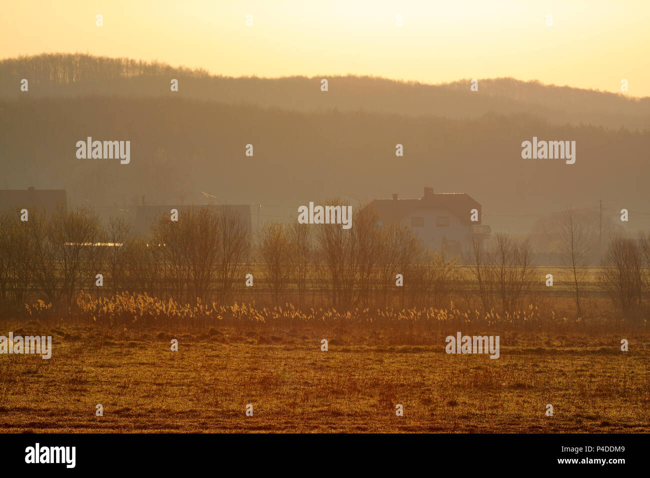 Warm hazy sunrise over village. Poland, The Holy Cross Mountains. Stock Photo