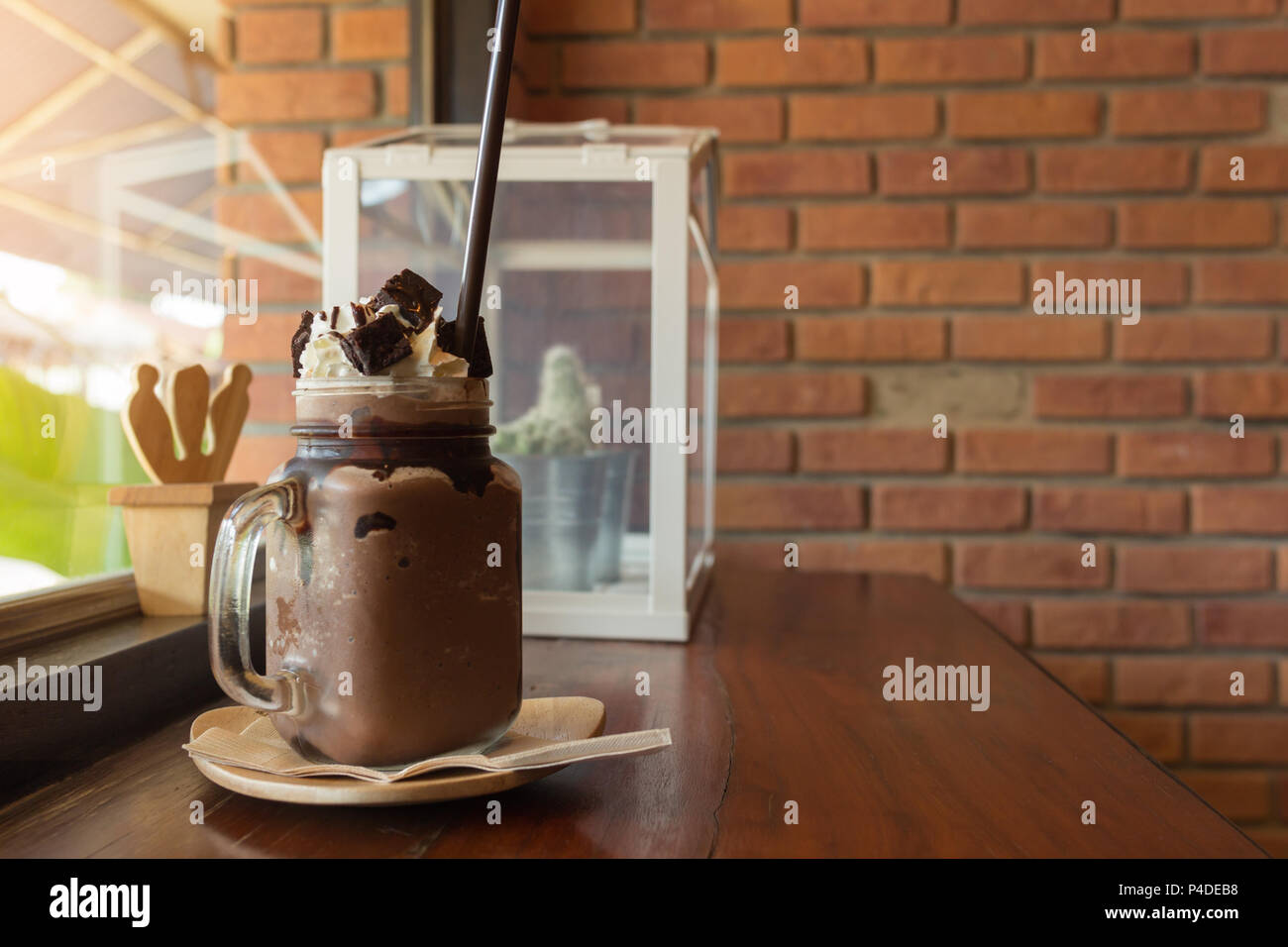 Dark chocolate milk shake with whipped cream brownie on wood table, window cafe background, beverage summer. Stock Photo