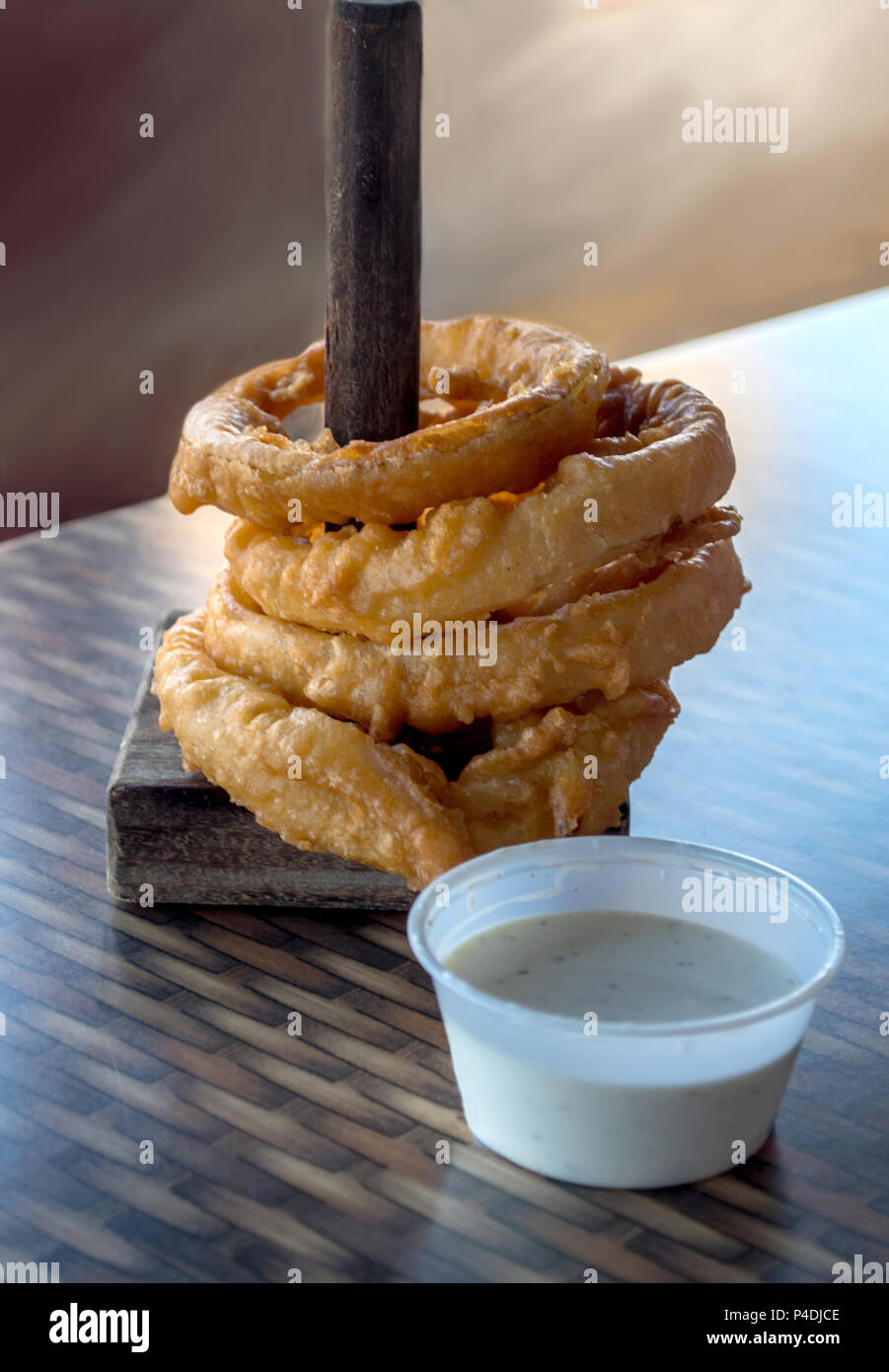 stack of crispy deep fried onion rings served on a spool with dipping