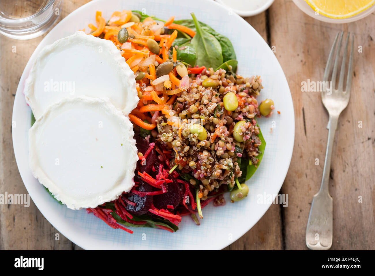 Goats cheese, beetroot, wholegrain, quinoa and edamame, carrot and pumpkin seeds salad with yoghurt dressing Stock Photo