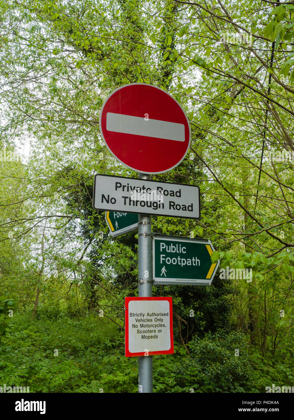 Multiple signs on a single signpost on a public footpath and private road in the UK. Stock Photo