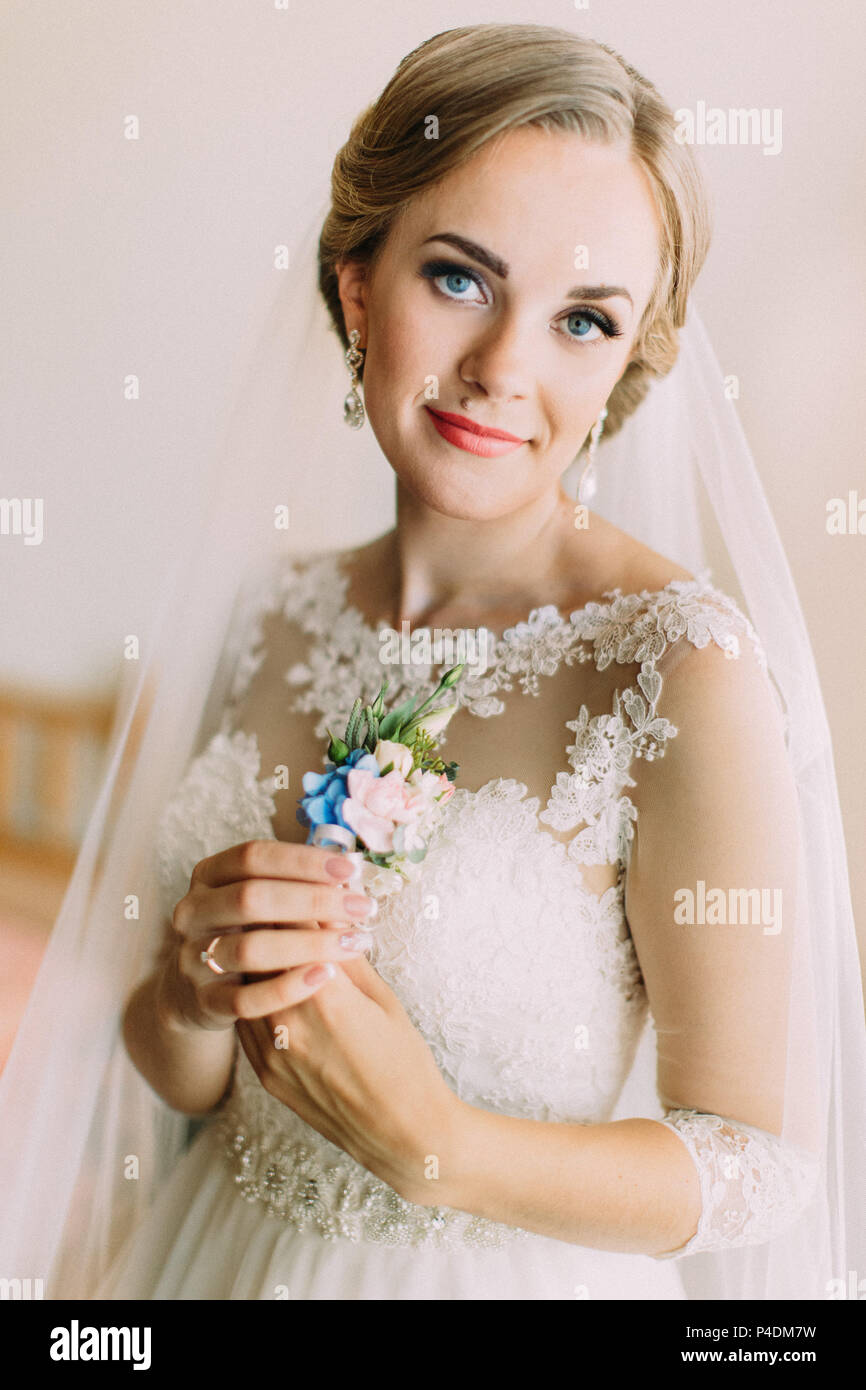 The portrait of the beautiful bride holding the blue boutonniere. Stock Photo