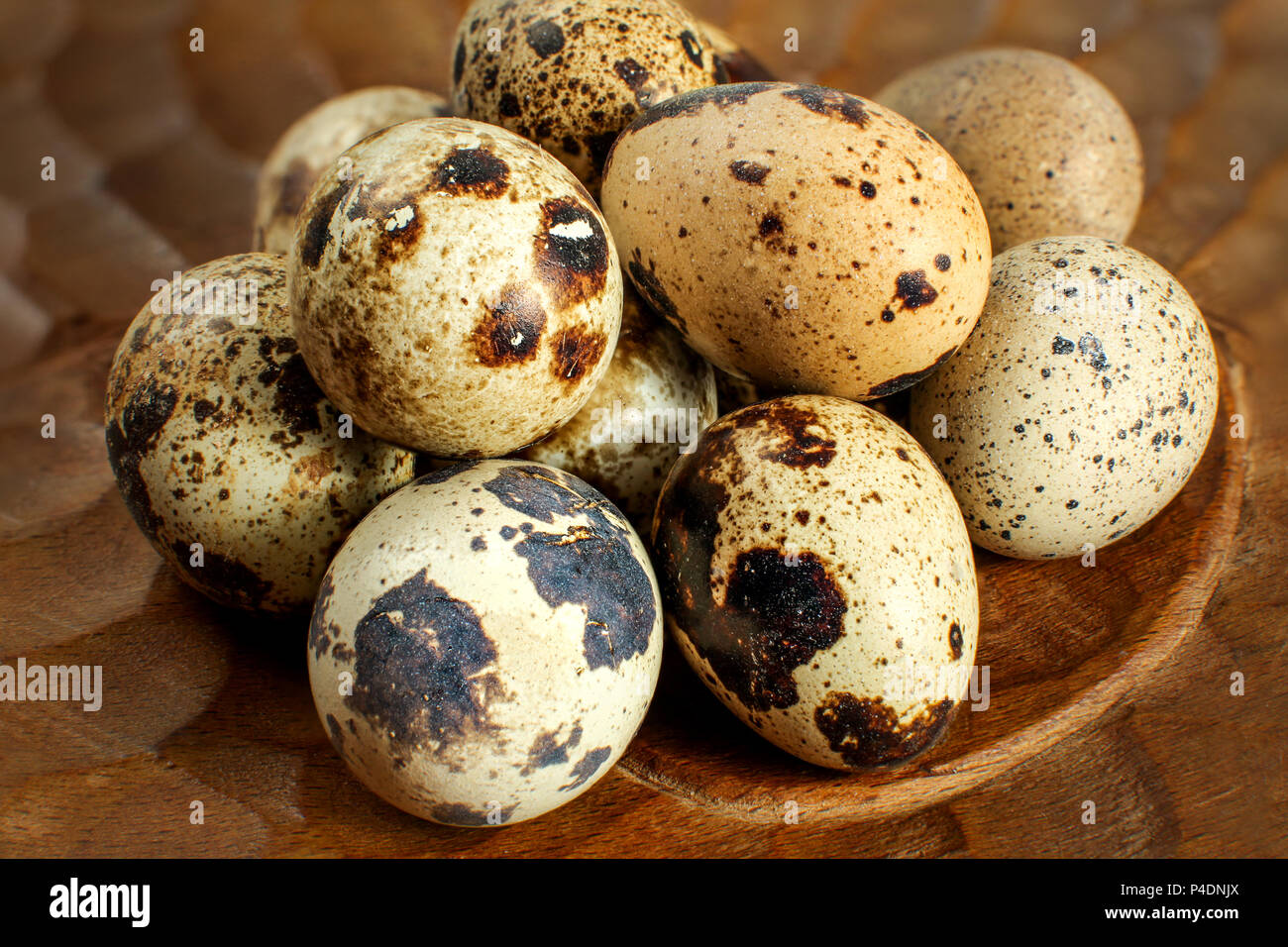 Detail view on quail eggs placed on wooden plate. Stock Photo