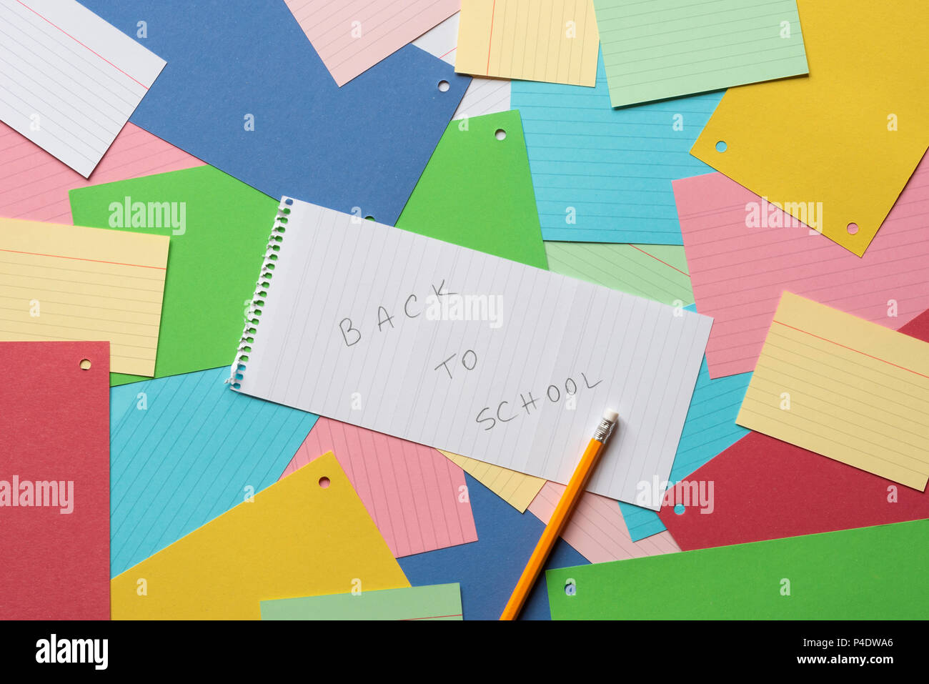 Notebook sheet with the message back to school against a background of colorful paper notes Stock Photo