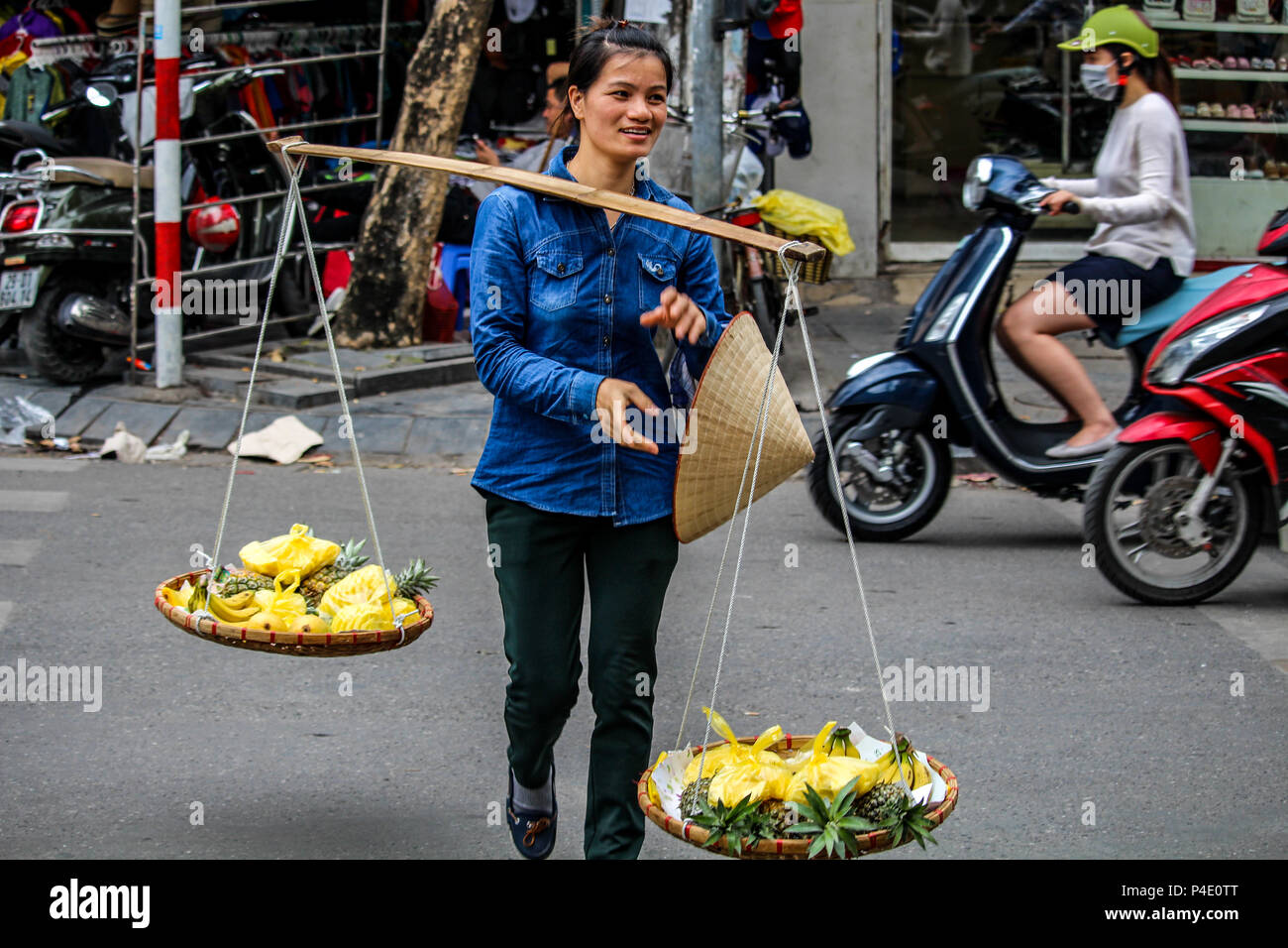 Hanoi, Vietnam - March 15, 2018: Girl selling fruits on the trafficked streets of Hanoi Stock Photo