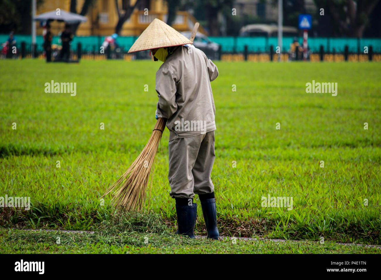 Hanoi, Vietnam - March 15, 2018: Gardener cleaning the grass between the Vietnamese government building and the Ho Chi Min mausoleum Stock Photo