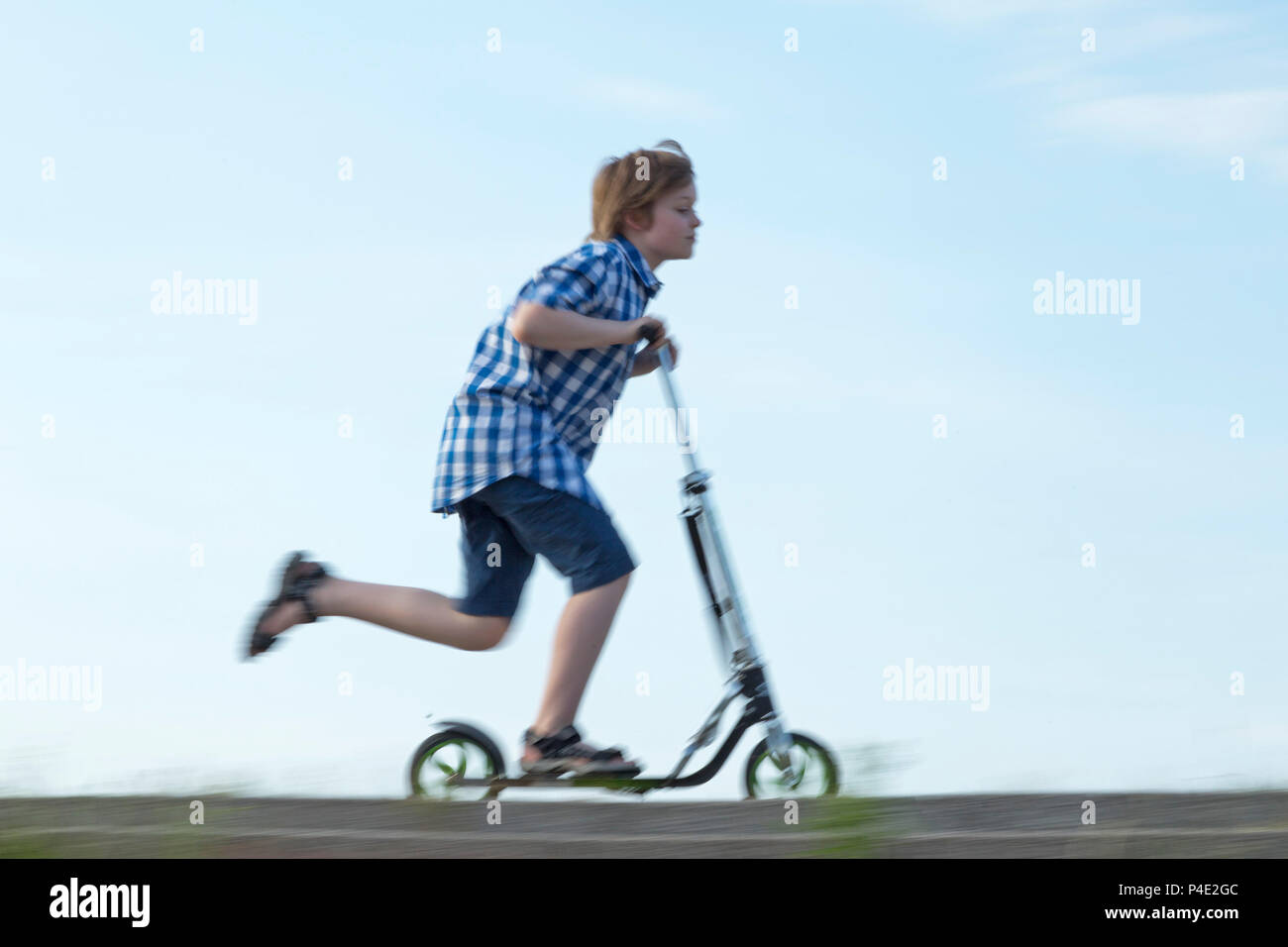 young boy riding his scooter Stock Photo