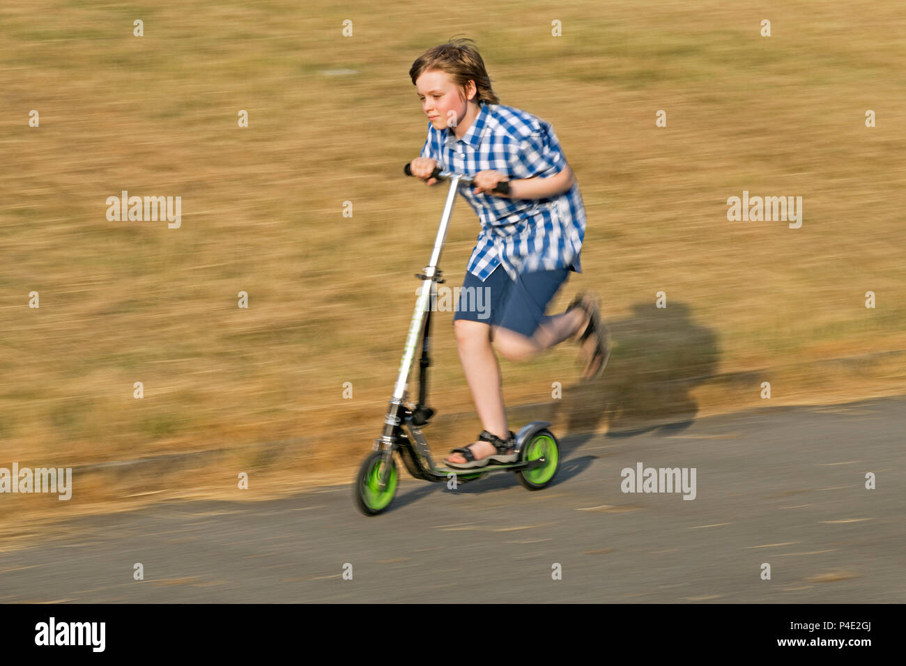 young boy riding his scooter Stock Photo