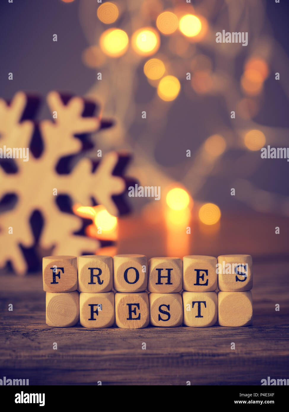German Merry Christmas on wooden dices with blurred lights and decoration Stock Photo