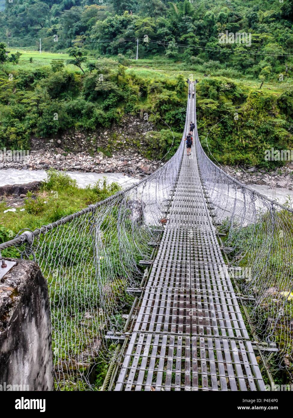 Suspension bridge over Marsyangdi river, Rainy weather near Besisahar, Annapurna circuit trek in Nepal Stock Photo