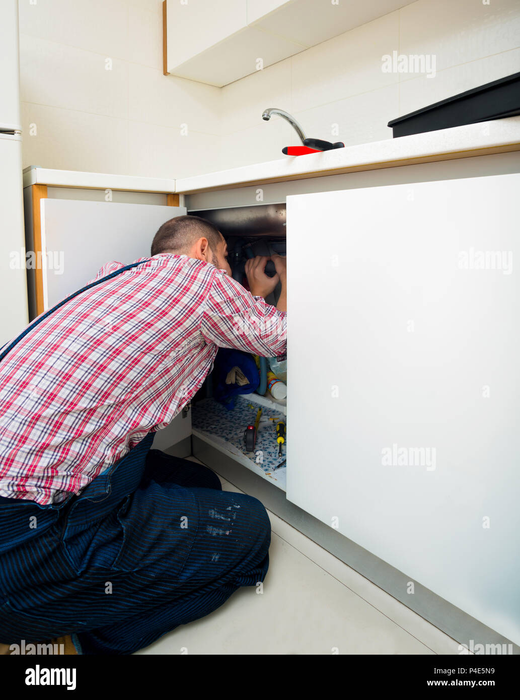 Plumber fixing a sink in kitchen with wrench Stock Photo Alamy