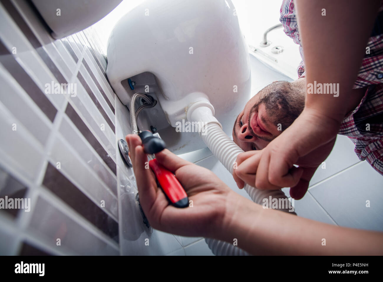 Plumber fixing a sink in bathroom with wrench Stock Photo