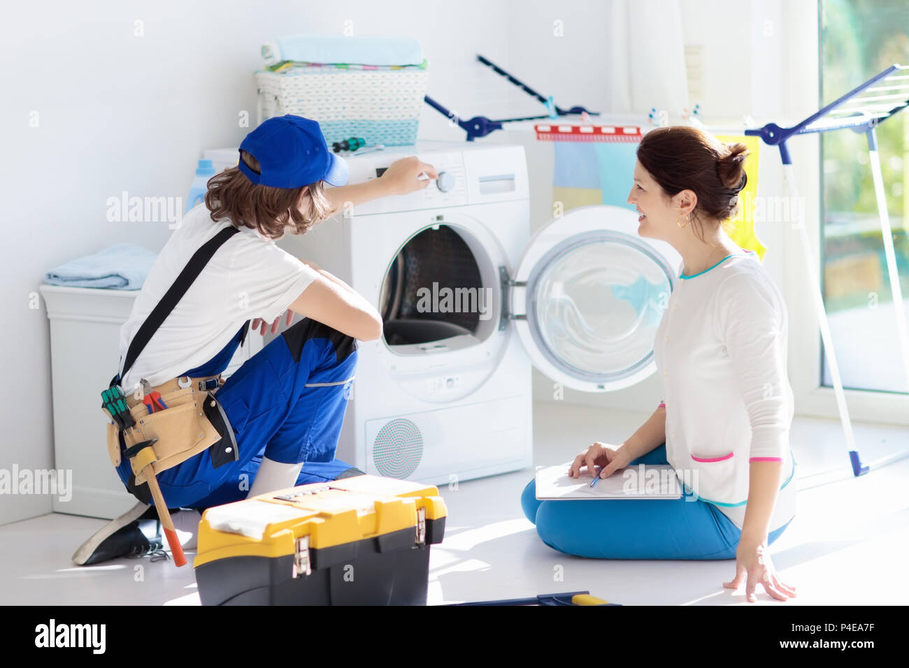 Washing machine repair service. Young technician examining and repairing  tumble dryer. Woman looking at broken household appliance. Plumber with  custo Stock Photo - Alamy