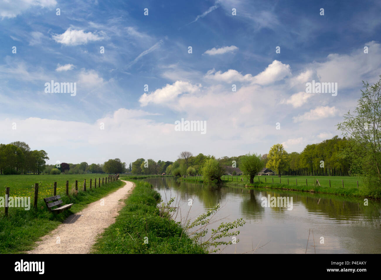 Authentic Dutch landscape with river Kromme Rijn, walkway, blue sky, white clouds and trees on a sunny day Stock Photo