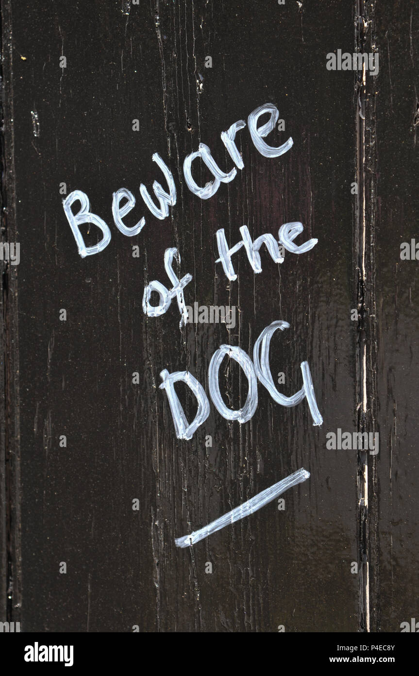 Beware of the dog chalk writing on a black painted wooden fence Stock Photo