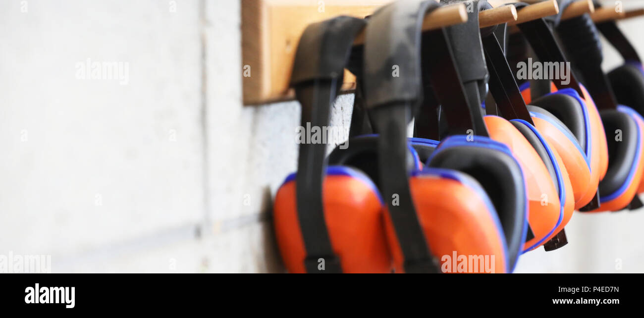 row of orange ear muffs ear protection on a rack. workplace health and safety deafness concept. safe work practice. Stock Photo