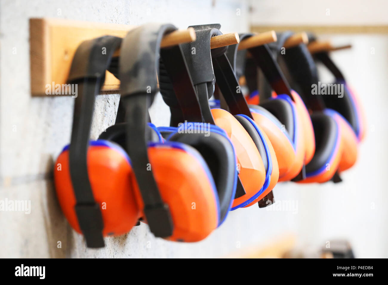 row of orange ear muffs ear protection on a rack. workplace health and safety deafness concept. safe work practice. Stock Photo