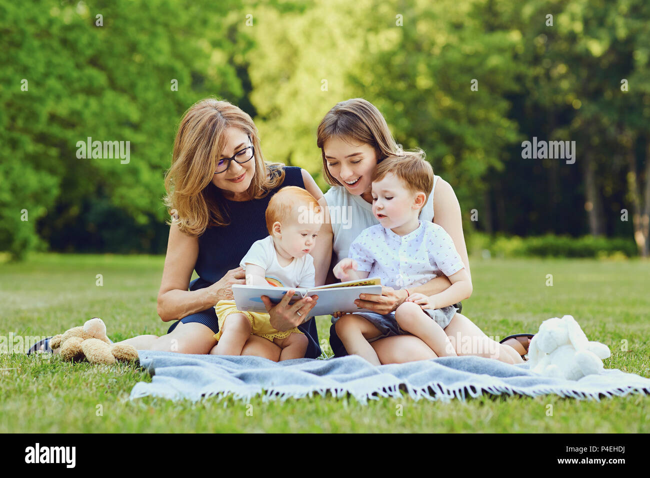 A family is reading a book on the grass. Stock Photo