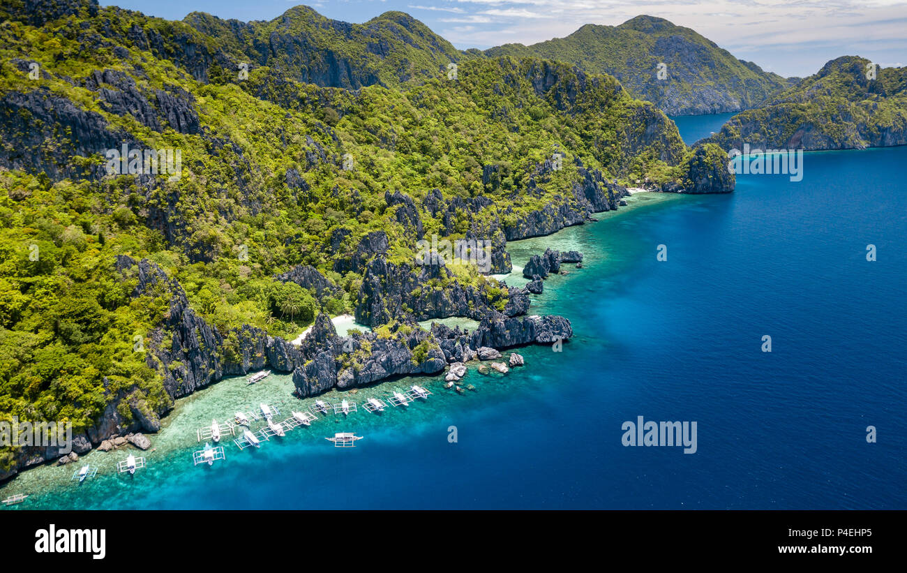 Aerial drone view of tourist boats over a tropical coral reef and small sandy because in the Bacuit Archipelago Stock Photo