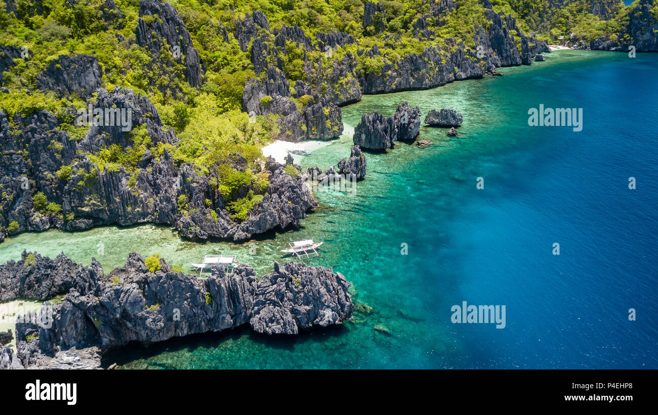 Aerial drone view of tourist boats over a shallow tropical lagoon surrounded by jagged cliffs Stock Photo