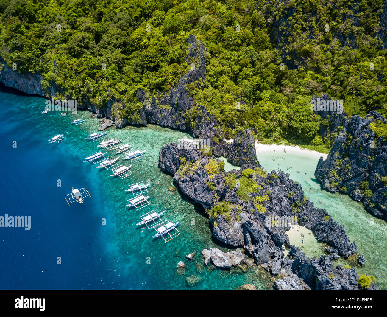 Aerial drone view of large numbers of tourist boats next to a tropical lagoon and beach in El Nido, Palawan Stock Photo