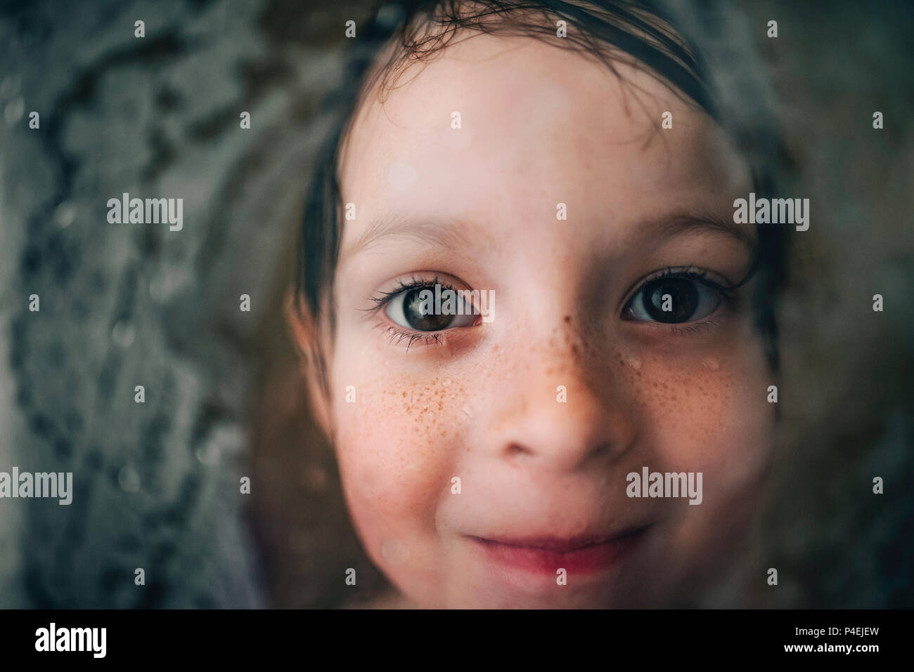 Portrait of a smiling girl looking through the wet shower glass Stock Photo
