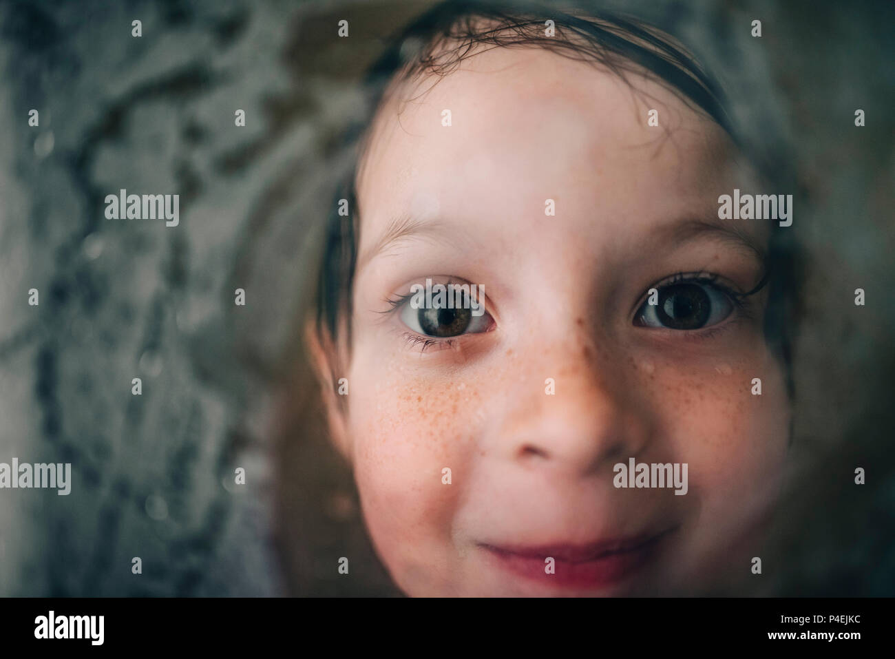 Portrait of a smiling girl looking through wet shower glass Stock Photo